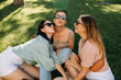 © Bostan Natalia - Group of friends outdoors, having good time, sitting on green grass, laughing, wearing sunglasses.