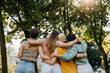 © Bostan Natalia - Group of four women in a park, hugging together from behind.