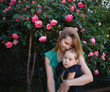 © Aleksandra Iarosh - mom hugs her little daughter against the background of a rose bush