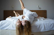 © Aleksandra Iarosh - mom and daughter lie on the bed in white hotel robes after a shower
