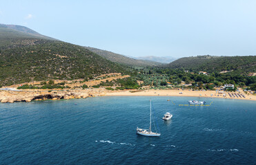 Aerial view of two anchored yachts at mediterranean sea with beautiful island landscape at background