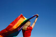 © Aleksandra Iarosh - girl with lgbt flag behind her back against a bright blue sky