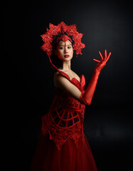 Canvas Print - Full length  portrait of beautiful young asian woman wearing red corset, long opera gloves and ornate gothic queen crown. Graceful posing isolated on a dark studio background.