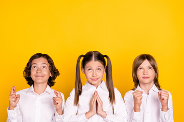 Sticker - Photo of three hopeful dreamy kids crossed fingers look empty space wear white shirt isolated yellow color background