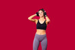 © Viorel - The girl with athletic body standing in front of the camera in sports clothes, holding the headphones with her hands listening the music.