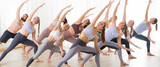 Group of young sporty attractive people in yoga studio, practicing yoga lesson with instructor, stretching on floor in Trikonosana, triangle yoga pose. Healthy active lifestyle, working out in gym.
