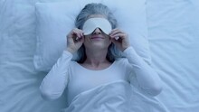 Happy Senior Woman Putting On Sleep Eye Mask Relaxing At Night, Bedtime Routine