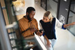 © Wavebreak Media - Two diverse male and female business colleagues talking and using smartphone