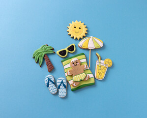 Wall Mural - Gingerbread man lying on blue background along with other summer theme cookies