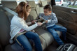 © didesign - Family toddlers dispute between brother and a sister over a digital tablet in the cars backseat
