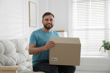 Wall Mural - Happy young man with parcel at home