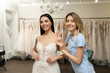 © New Africa - Woman helping bride wear wedding dress in boutique