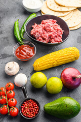 Wall Mural - Ingredients for beef meat mexican tacos , corn tortillas, chili pepper, avocado, meat  on textured grey background, side view.