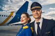 Smiling pilot and a flight attendant standing at the aerodrome