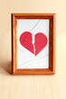 The paper heart is torn in two. Picture in photo frame with damaged glass