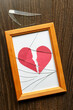Shards of glass on the table next to the photo frame. Two halves of red paper heart