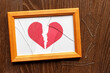 Photo frame with broken glass. The paper heart is torn apart.
