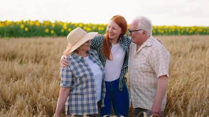 Wall Mural - Family business concept grandparents farmers and their beautiful niece in the middle of a large wheat field happy hugging each other