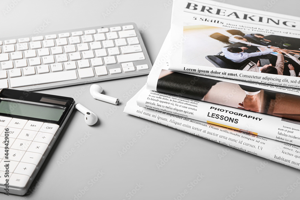 Composition with newspapers and earphones on light background
