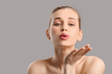 Wall Mural - Portrait of beautiful young woman blowing kiss on grey background