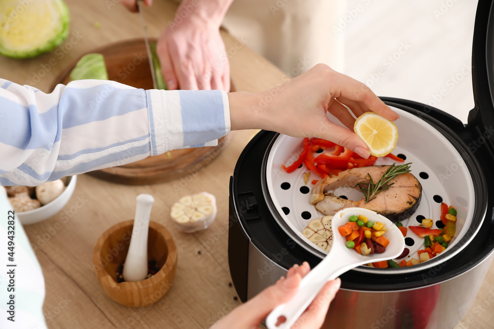 Woman squeezing lemon onto fish in multi cooker