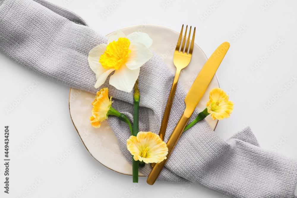 Beautiful table setting with narcissus flowers on white background