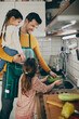 © Drazen - Happy father and daughters wash lettuce while preparing salad in the kitchen.