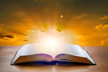 Wall Mural - Holy Bible book on a wooden desk with sunset light background