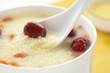 A spoon scooping up some red date millet rice congee in a bowl, depth of field