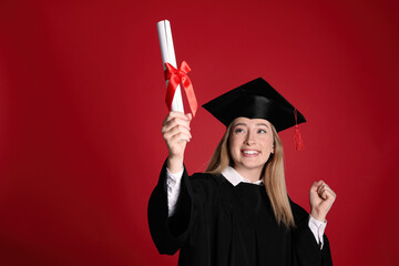 Wall Mural - Happy student with diploma on red background