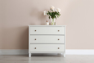 Wall Mural - White chest of drawers with bouquet and candle near beige wall