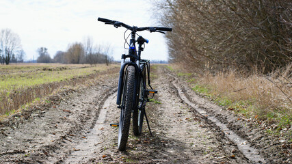 Wall Mural - Mountain bike. stands on a field road. spring or autumn. concept of cycling, repair or breakage, sports, outdoor activities. bike on trail, front wheel in focus. space for text