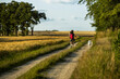 © mcBagus - woman walking with a dog white swiss shepherd by path between fields in sunny day