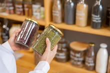 A Woman Holds Glass Jars Of Cereals In An Eco Friendly Store. The Concept Of A Grocery Store Without Plastic Disposable Packaging