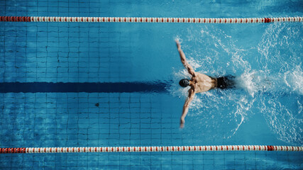 aerial top view male swimmer swimming in swimming pool. professional determined athlete training for