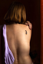 The Naked Back Of A Young Woman With Red Hair And A Tattoo On Her Shoulder