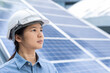 © Bond_JP - Close up, side view portrait with copy space of a determined woman wearing white safety helmet and blue denim shirt, standing near solar panels. Asian female engineer and sustainable energy concept.
