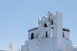 church with two bells White and blue top of buildings in Pyrgos Santorini, Greece with blue sky in a sunny warm day in July 2021.