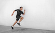 © Maridav - Sport athlete training running fast with explosive sprint for competition. Man runner working out at fitness gym outdoor white wall background.