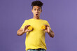Holidays, vitamins and vacation concept. Portrait of funny and cute young 25s man fool around, showing breast with pieces of oranges over chest, look ashamed or shocked, purple background
