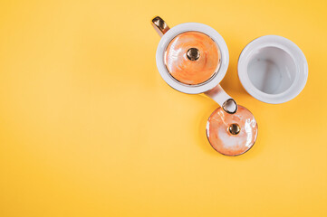 Sticker - Top view of an orange covered teapot, cup and a cover on an orange isolated background