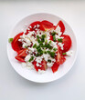 Fresh tomato salad with cottage cheese and scallions in white bowl on white background. Home made food. Top view. Tasty and healthy meal.
