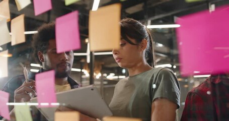 Creative hipster multiethnic team brainstorming near strategy board with colorful stickers. Young designers or developers coming up with ideas 4k footage