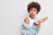 © wayhome.studio  - What do you mean by this. Puzzled clueless African American woman shrugs shoulders looks away with displeased expression cannot understand something wears denim shirt isolated on white wall.