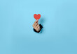 Woman hand holding heart on blue background.