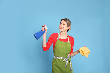 Sticker - Young housewife with detergent and rag on light blue background