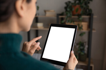 Close up view over shoulder woman holding tablet with white screen mockup, typing on touchscreen, using modern gadget, browsing apps, shopping or chatting online in social network, playing game