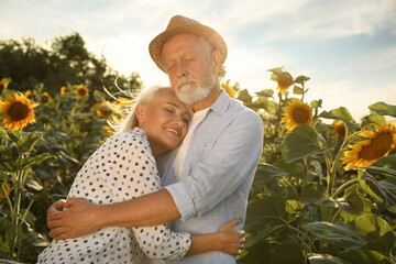 Sticker - Happy mature couple in sunflower field on summer day