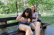 © hannamartysheva - Mom and her teenage daughter have fun laughing on a walk in a summer park. Using a smartphone