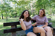 © hannamartysheva - Mom and her teenage daughter have fun laughing on a walk in a summer park. Using a smartphone